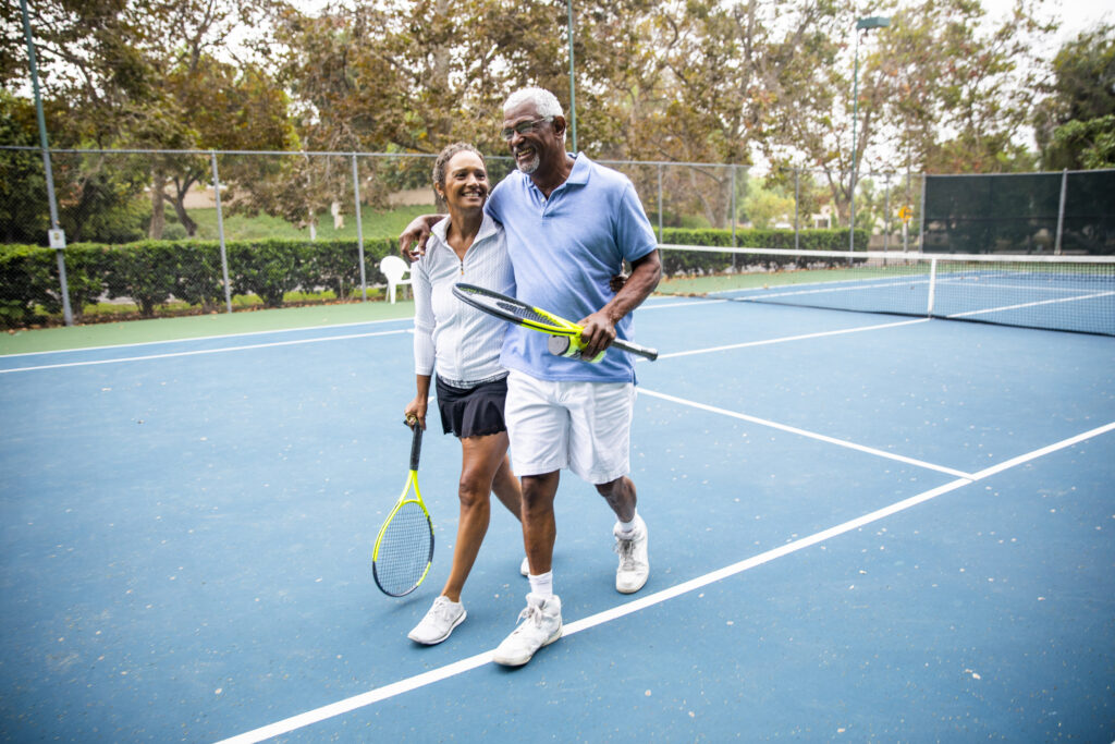active adult couple playing tennis outside