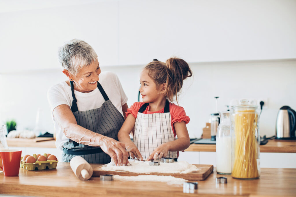 grandmother cooking with granddaughter in kitchen