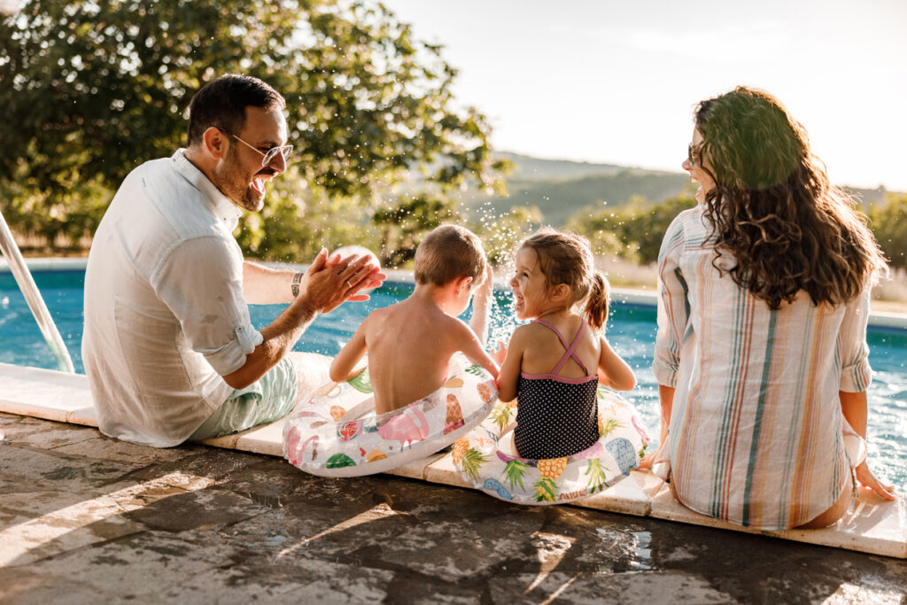 family sitting on edge of backyard pool