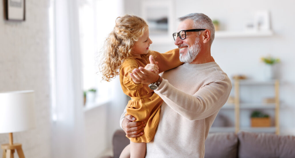 grandfather dancing with his granddaughter at home