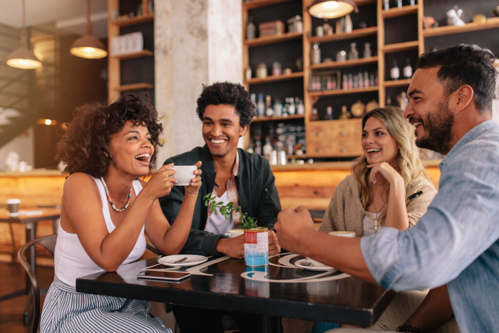 group of young people sitting in a coffee shop and smiling.