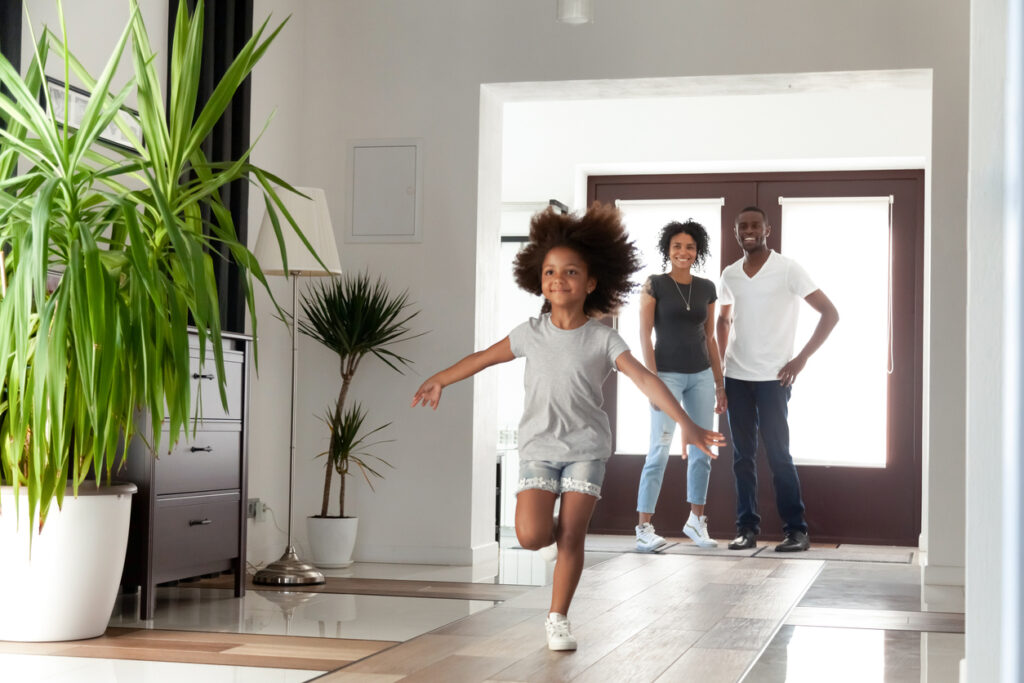 Excited little girl exploring big modern house, happy parents coming into new home