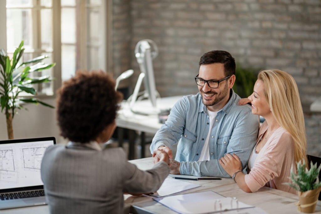 Happy couple handshaking with financial advisor on a meeting in the office. 