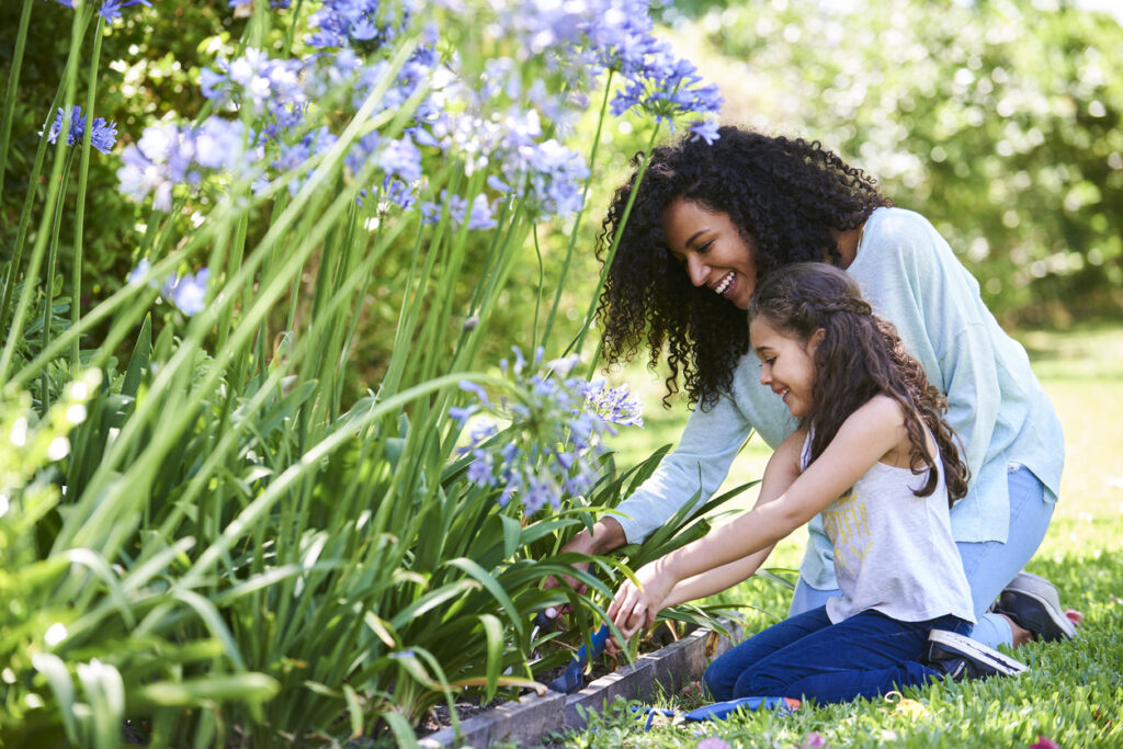 Smiling mother and daughter doing gardening outdoors