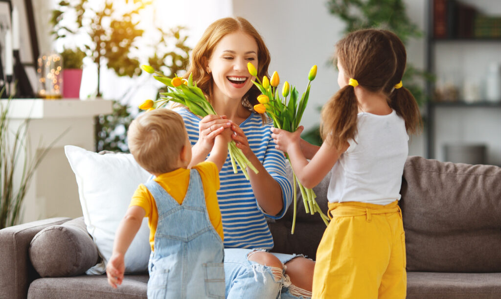 two kids giving their mother tulips