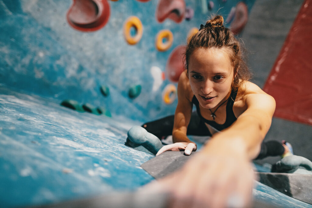 Strong woman climbing on boulder wall