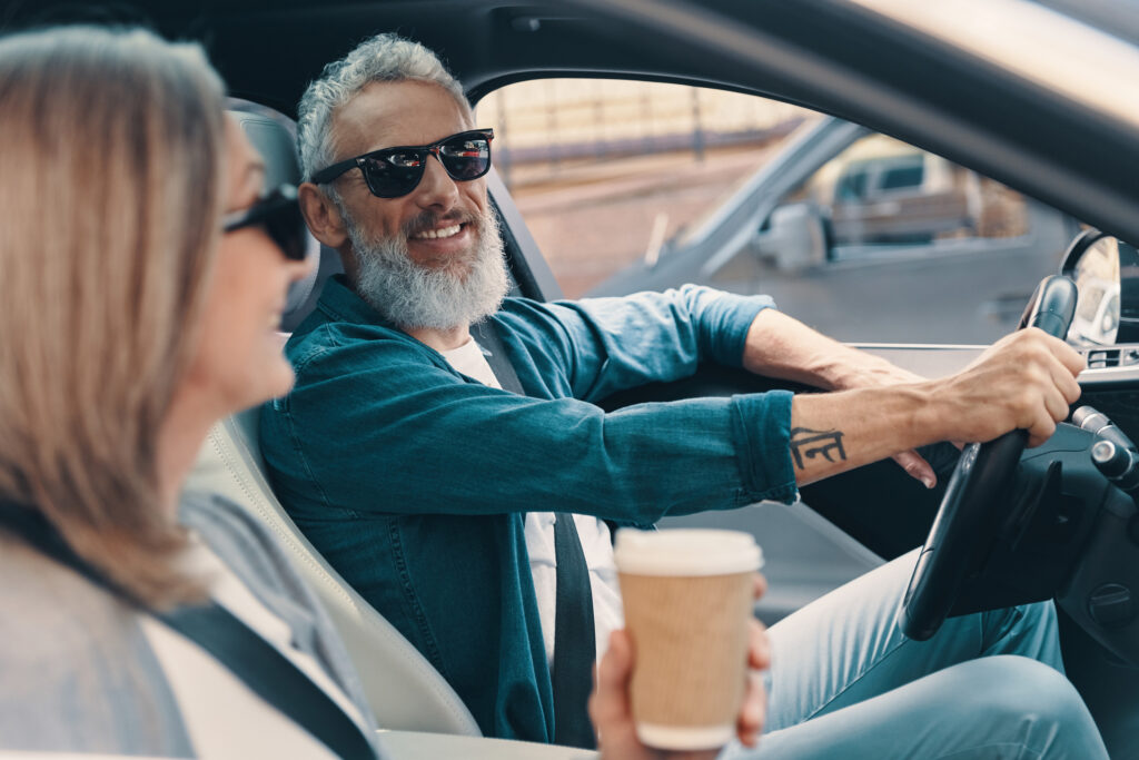 Carefree senior couple enjoying car ride while sitting on front seats of the car