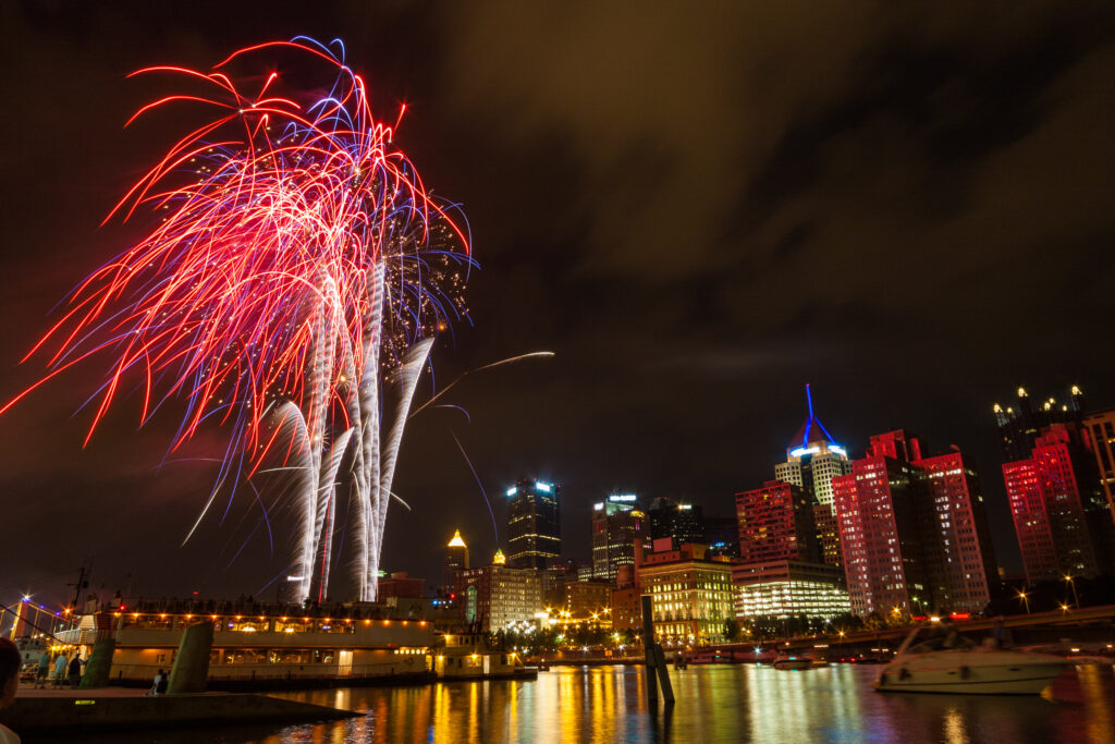 Pittsburgh, PA river view skyline at night with colorful firework.