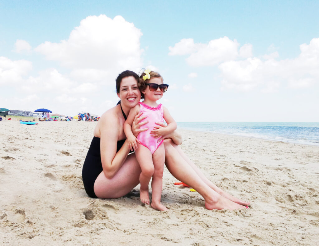 mother and daughter on a beach with the daughter wearing the mother's sunglasses