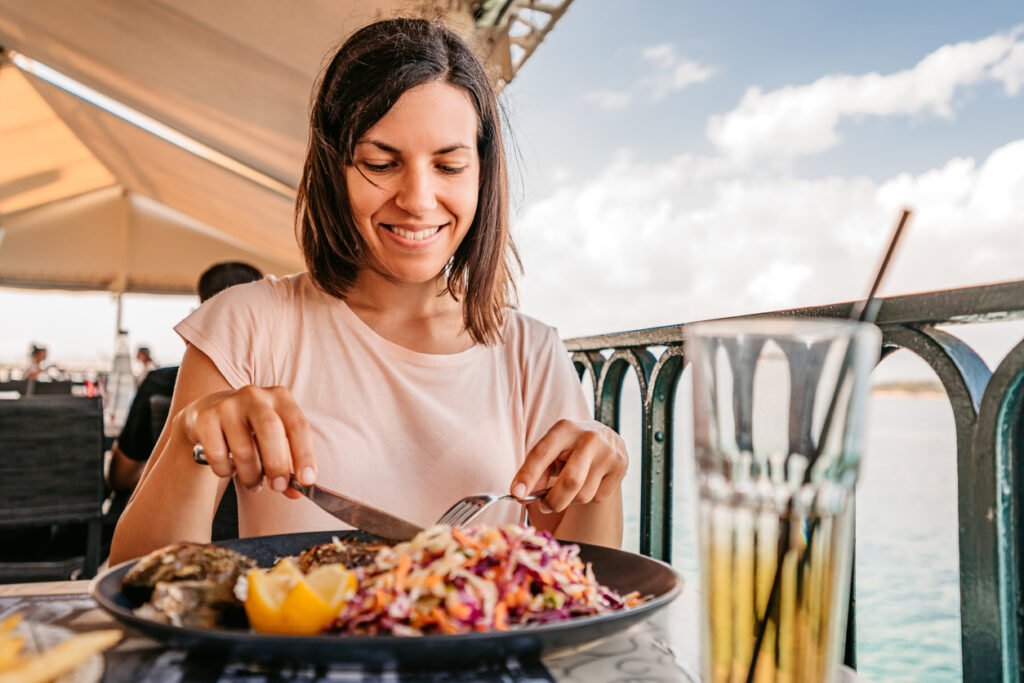 Beautiful young woman enjoying a meal by the sea.