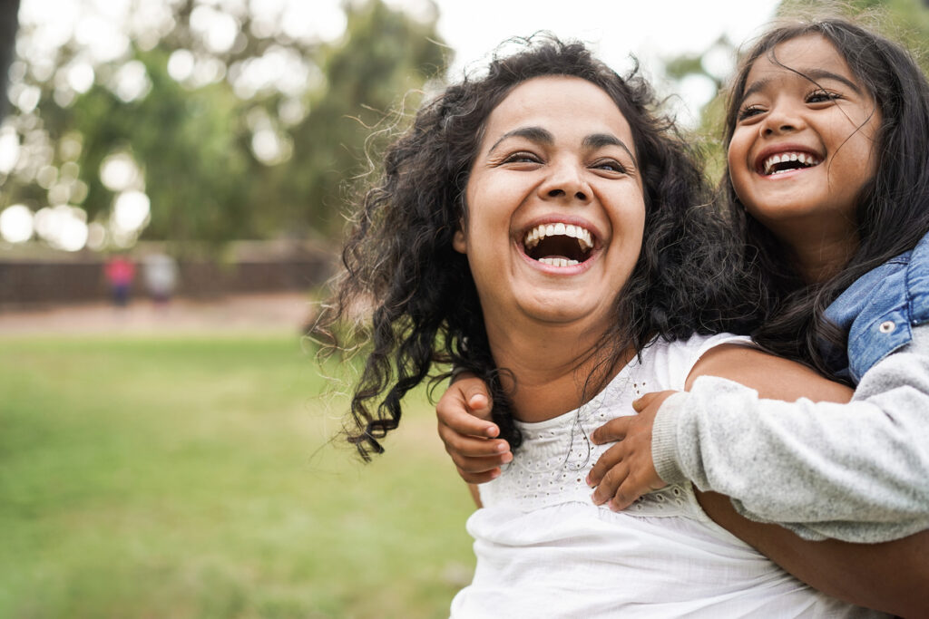 Happy indian mother having fun with her daughter outdoors
