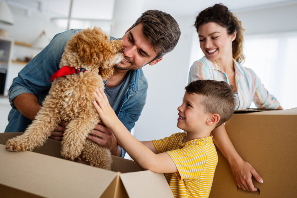 Happy young family unpacking cardboard boxes at new home. 