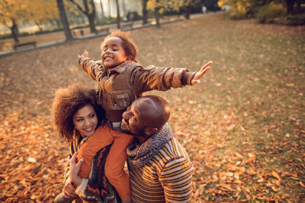 Happy African American family having fun in autumn park. 
