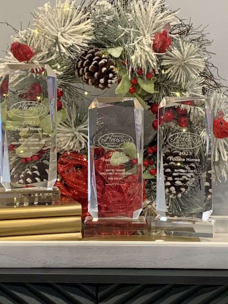 three awards for homebuilding in front of a christmas tree background