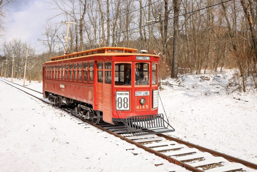 a historic trolley outdoors in the winter on a trolley track, as part of  the Pennsylvania Trolley Museum