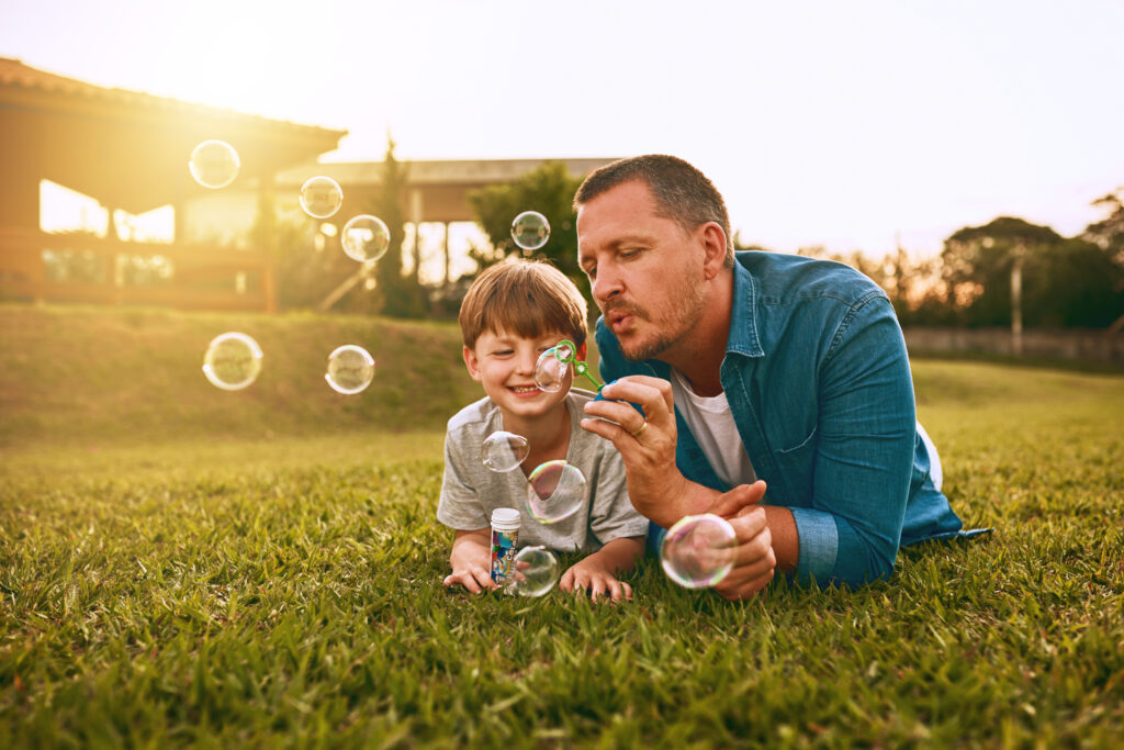 dad and son blowing bubbles in the grass