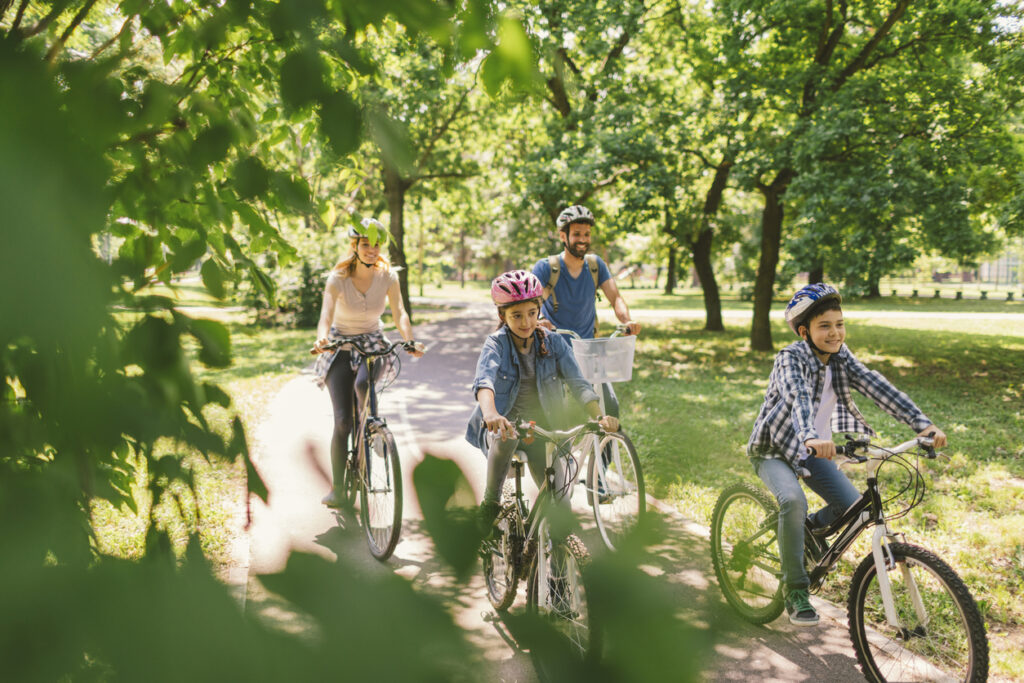 Family riding bicycle in the public park together. Cycling and enjoying the sunny day