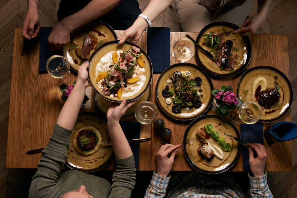 Flat-lay of human hands eating meals. People eat healthy food and drink alcohol. 