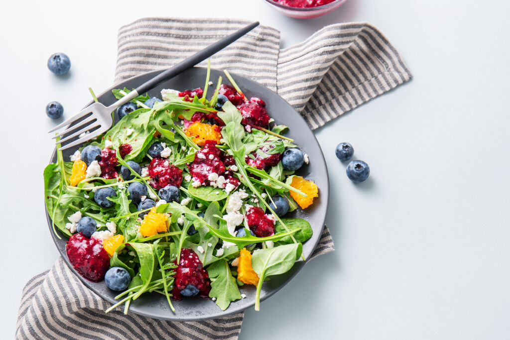 Tasty summer refreshing salad with salad leaves, feta, fruits, sauce and berries
