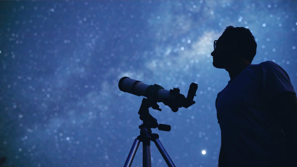 Astronomer with a telescope watching at the stars and Moon
