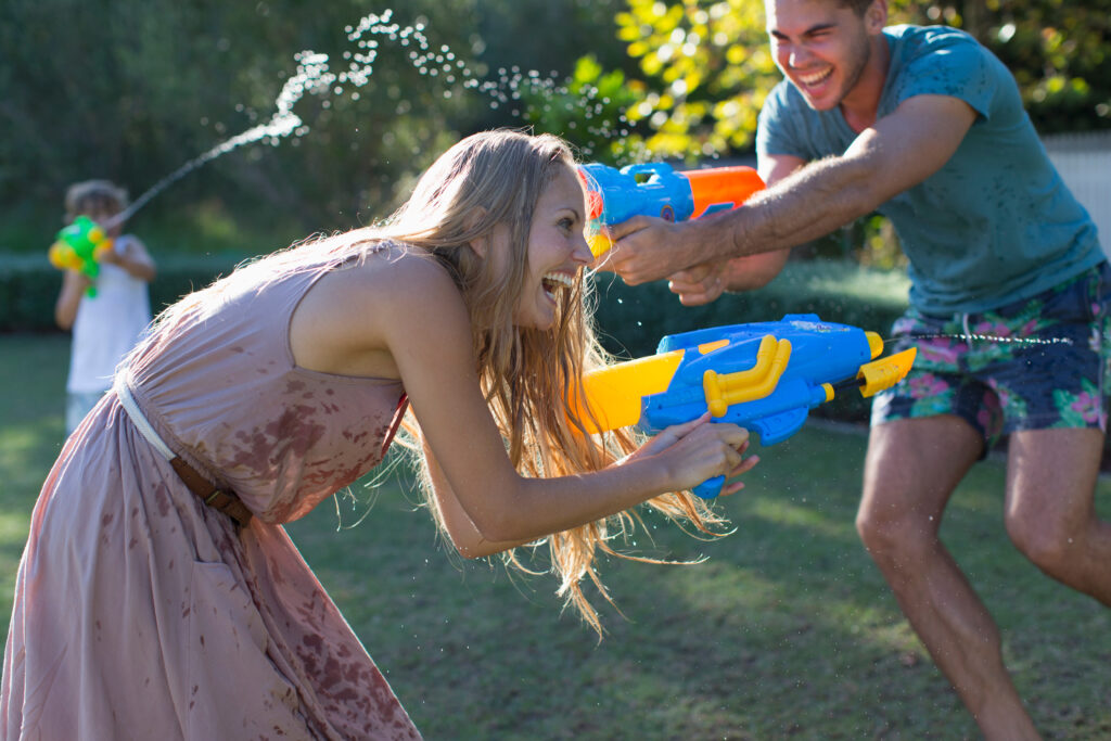 family playing with water guns in the back yard