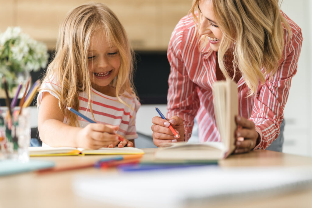 Happy woman drawing with her daughter and smiling at home