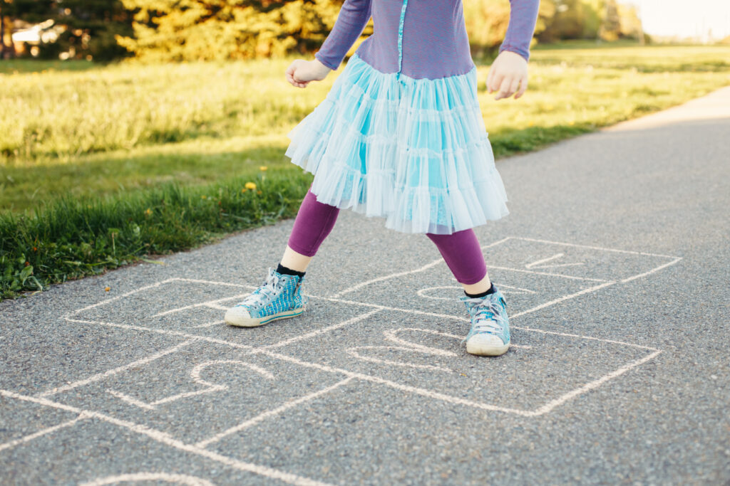 little girl playing hopscotch on the sidewalk