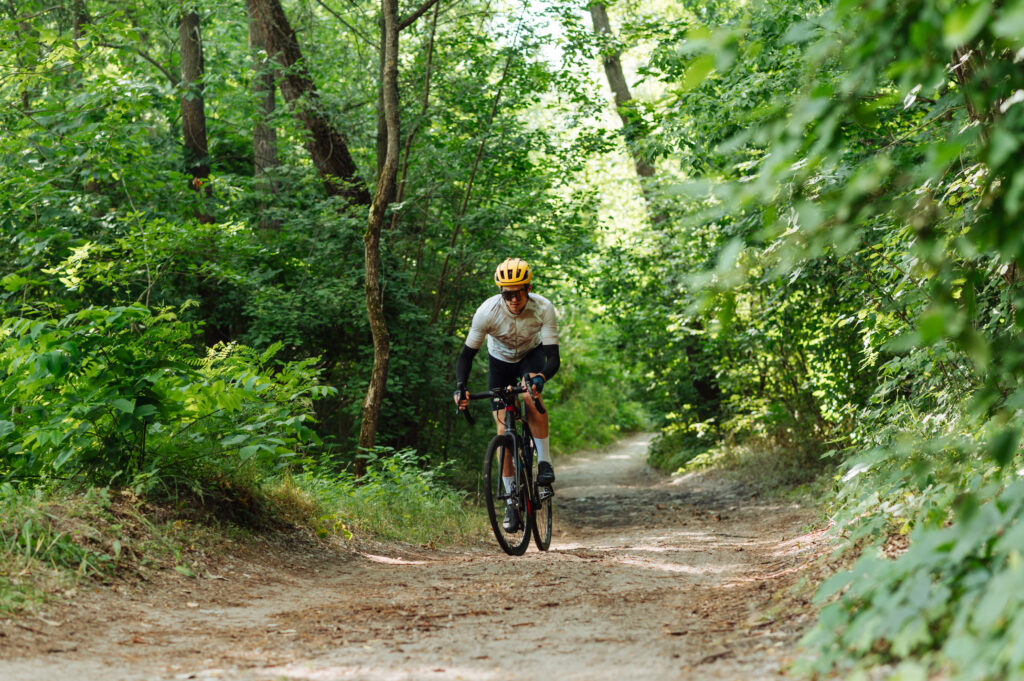 Cyclist in full gear rides on forest trails on a gravel bicycle.