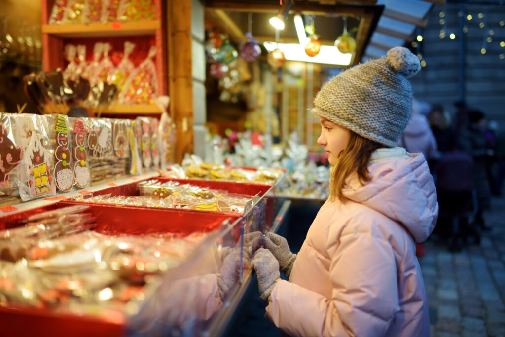 small girl looking at a holiday craft fair  booth outside