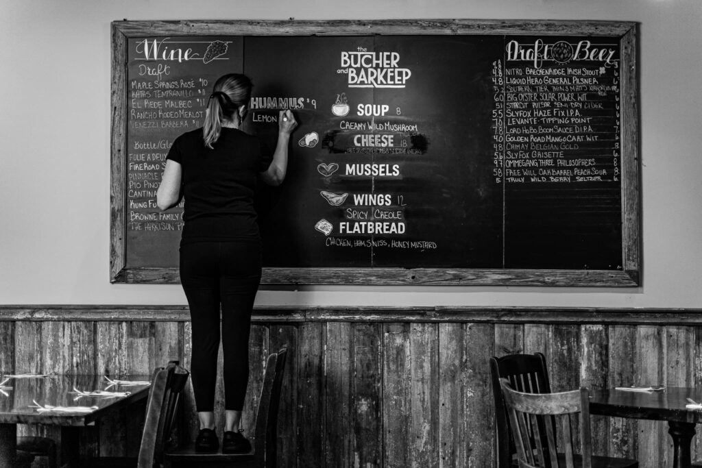 woman updating a menu board at the butcher and barkeep in philadelphia