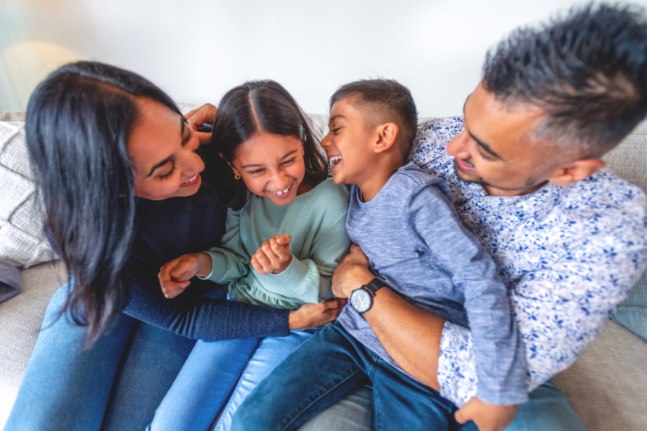 mom and dad laughing with kids on the couch