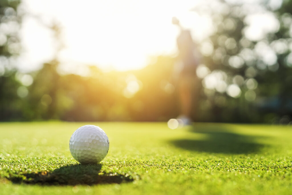 golf player putting golf ball into hole