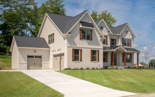 A modern two-story house with cream siding, black roof, brown shutters, a single-car garage, large windows, and a well-maintained lawn on a sunny day.