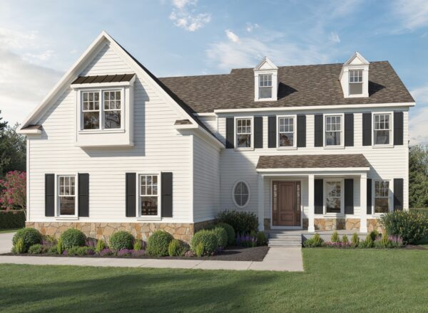 A two-story white house with black shutters, stone accents, dormer windows, and neatly trimmed bushes in front, under a blue sky.