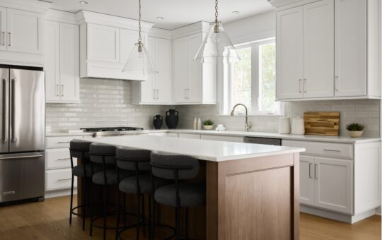 Modern kitchen with white cabinets, stainless steel appliances, a wooden island with four dark upholstered stools, glass pendant lights, and a window letting in natural light.