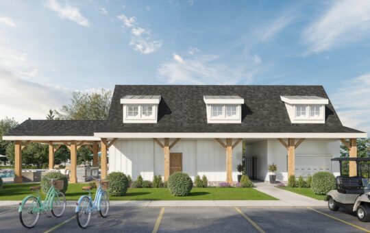 A modern farmhouse-style building with white siding, dark roof, and wooden posts. Two bicycles and a golf cart are parked in front, with green bushes and a pool visible to the side under a blue sky.